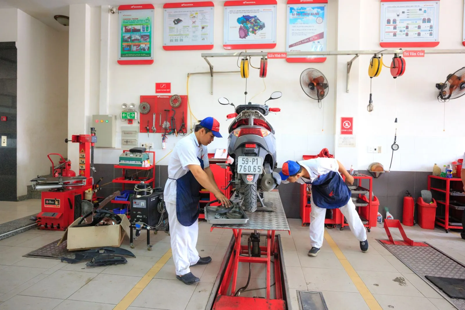 Mechanics performing maintenance on a motorcycle in a well-equipped auto repair shop.